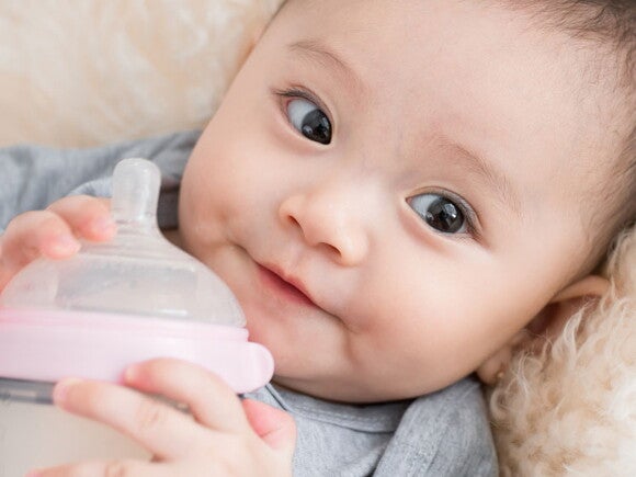 Baby holding feeding bottle