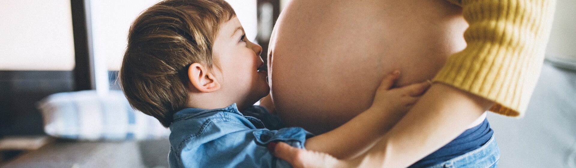 Boy kissing pregnant mom's tummy Boy kissing pregnant mom's tummy