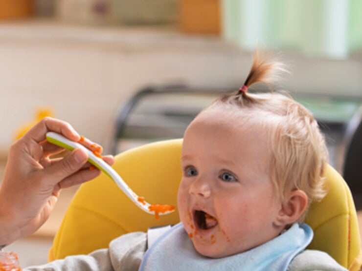 Mom feeding her baby with a spoon Mom feeding her baby with a spoon