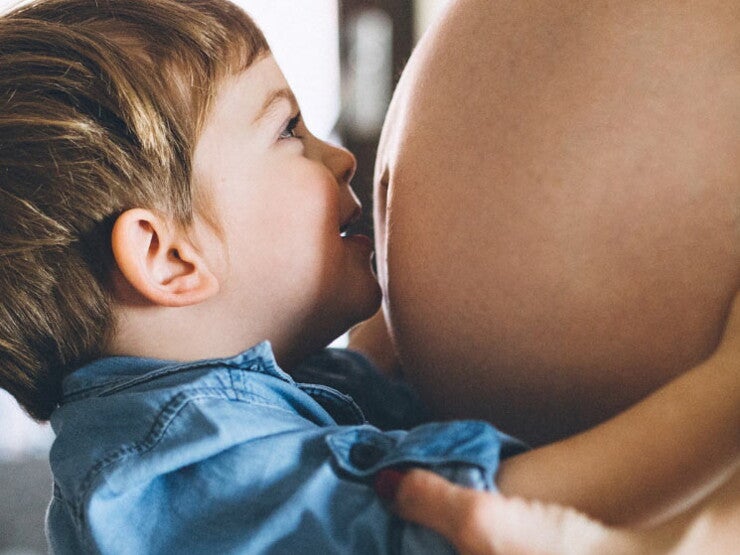 Boy kissing pregnant mom's tummy Boy kissing pregnant mom's tummy