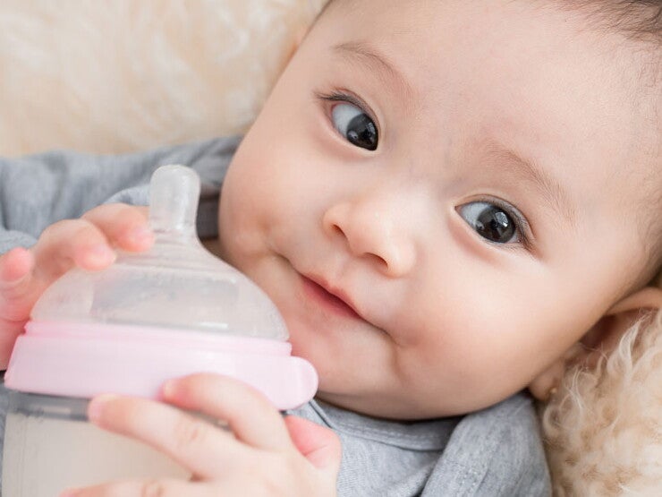 Baby holding feeding bottle