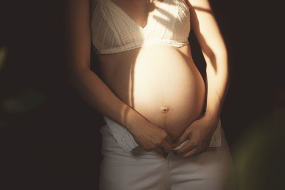 Een zwangere vrouw in zacht licht, die de zorgzame ondersteuning van Nestlé FamilyNes voor elke fase van het ouderschap symboliseert.